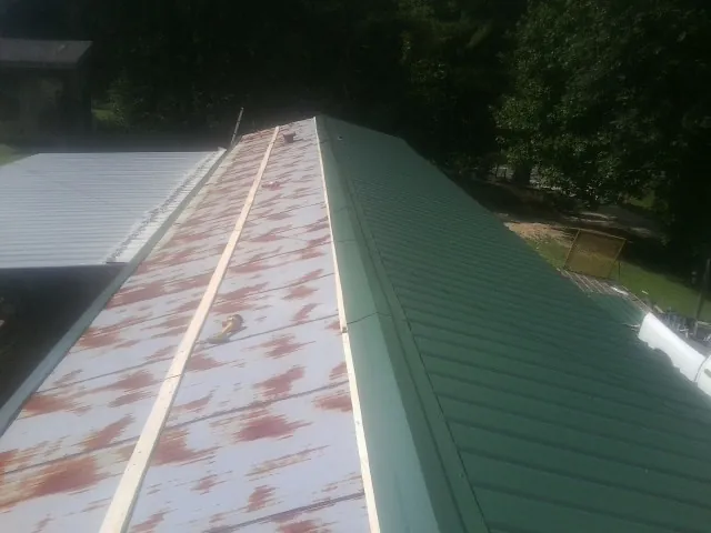 Old rusted panels beside newly installed green metal roofing — Wind Damage Roof Repair by Roofing Brothers in Fort Bridger