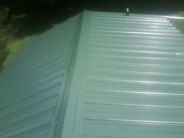 New green metal panels meeting at the ridge of a roof — Flat Roof Repair work by our crew in Fort Bridger