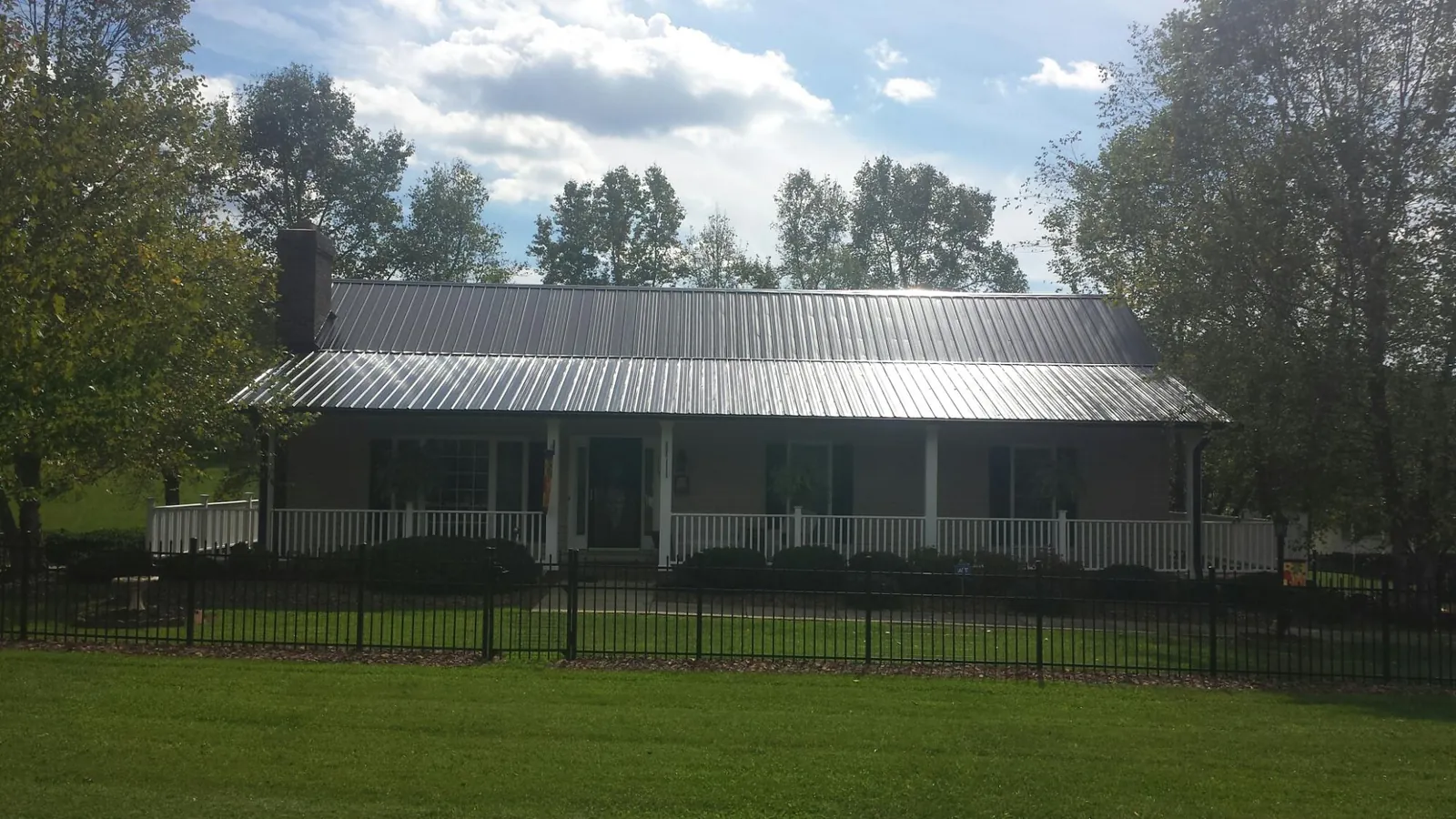 Gray metal roof on a brick ranch with a full width front porch — Gutter Guard Installation work by our crew in Fort Bridger