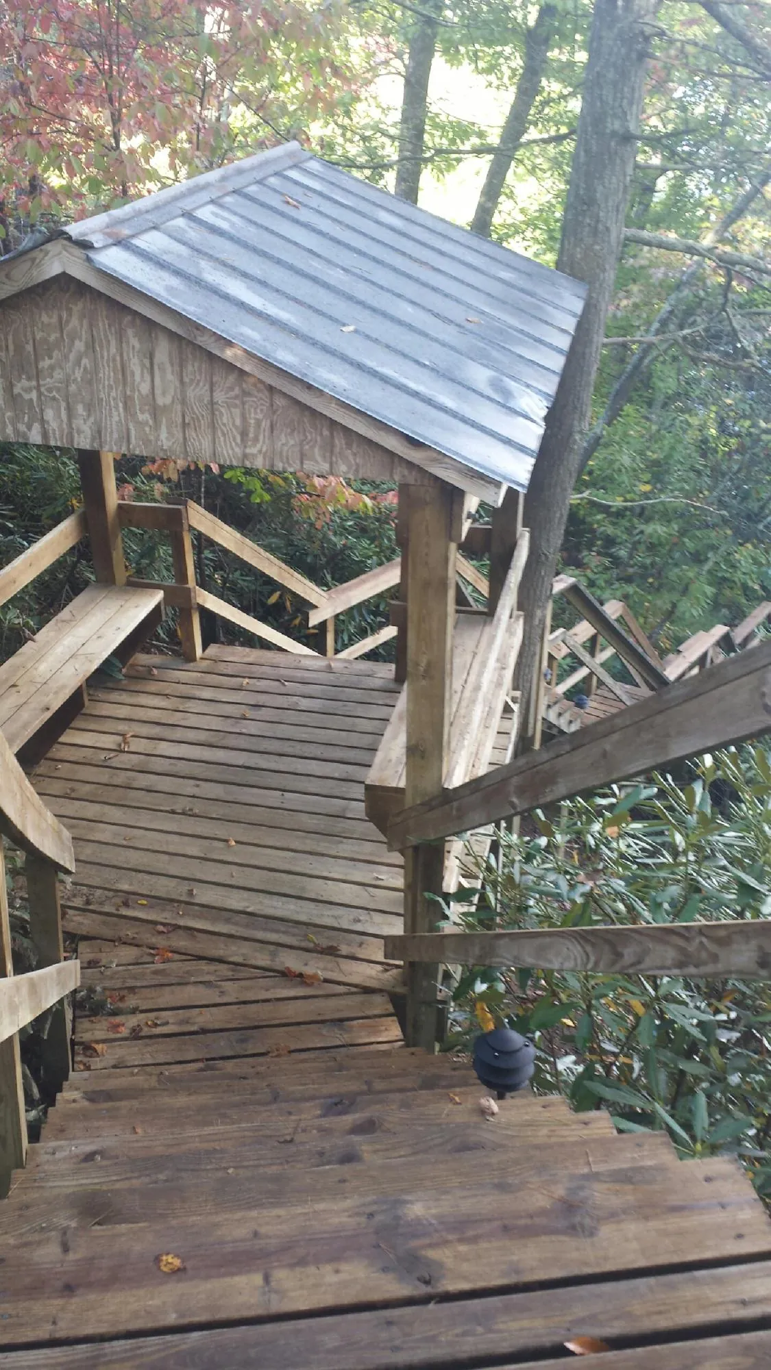 Metal roofed shelter over wooden steps on a wooded walkway — Skylight Repair & Installation work by our crew in Fort Bridger