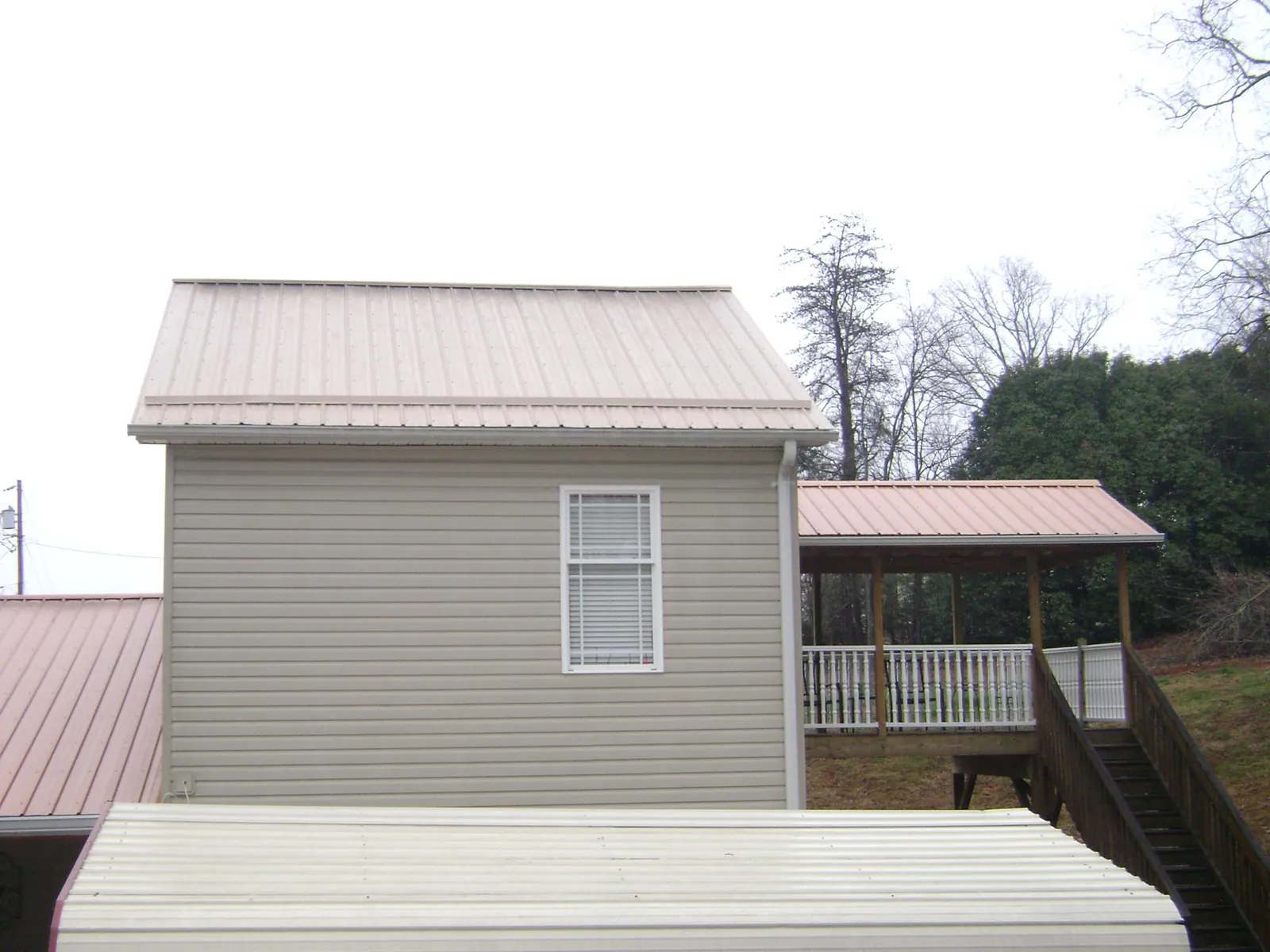 Tan metal roofs on a two story addition and attached porch, from a Roof Replacement job in Fort Bridger