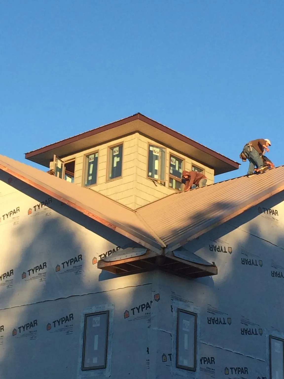 Roofers working around a rooftop cupola on a new metal roof at sunset — Roof Waterproofing in Fort Bridger by Roofing Brothers